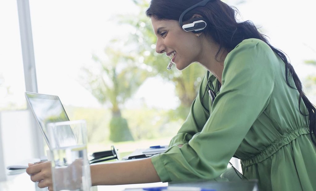 Smiling businesswoman with headset at laptop