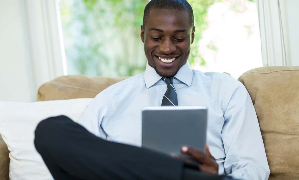 Young man sitting on sofa and using digital tablet
